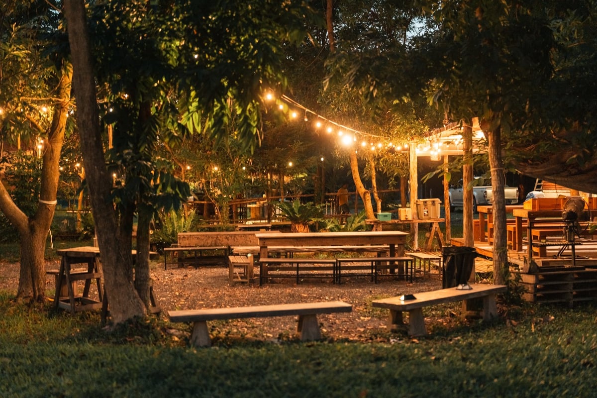 Cozy outdoor dining area set up for a rustic BBQ party with relaxed camp style atmosphere where friends and families gather to enjoy grilled food under the lights